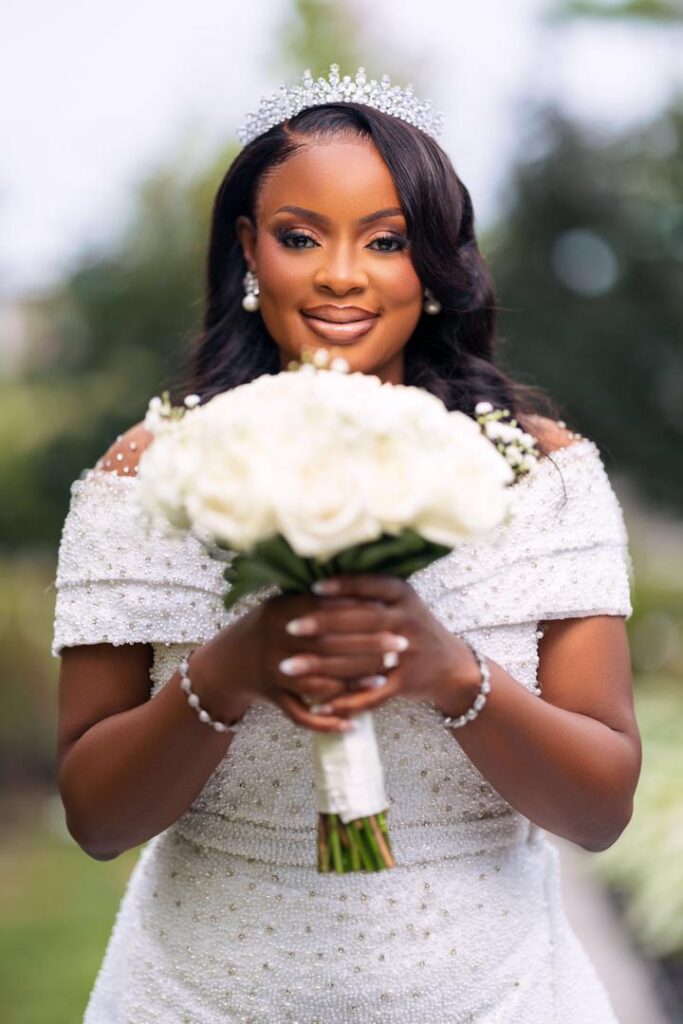 A bride holding her bouquet with a crown on her head.
